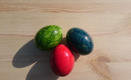 Easter eggs lie on a light wooden boardの写真素材