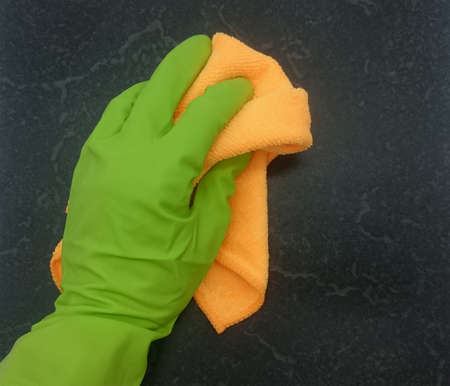 Hand in green rubber glove with duster