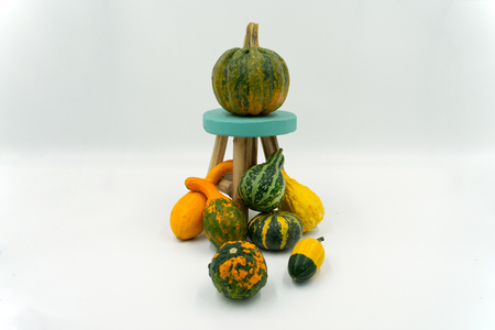 Various types of ornamental pumpkins with decorative little wooden chair. Studio shot on white backgroundの写真素材