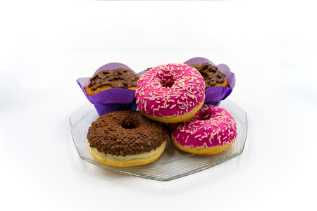 Pink and chocolate donuts and muffins on a glass plate. Studio shot on white backgroundの写真素材