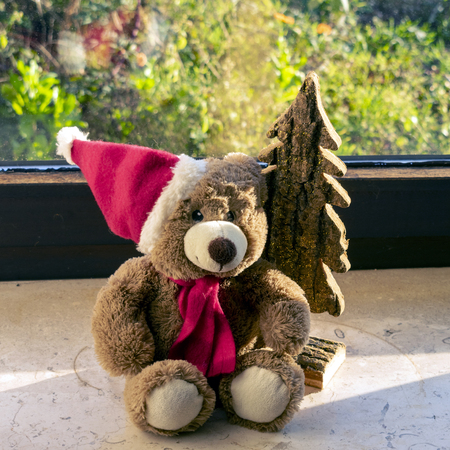 Christmas teddy bear with christmas tree on the windowsillの写真素材
