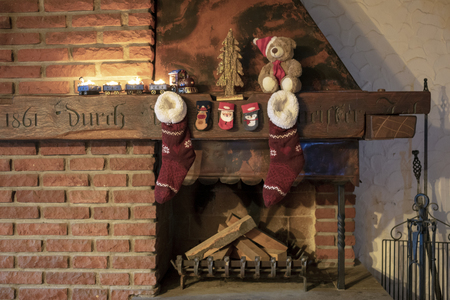 Rustic fireplace with Christmas train with burning candles and Christmas stockingsの写真素材