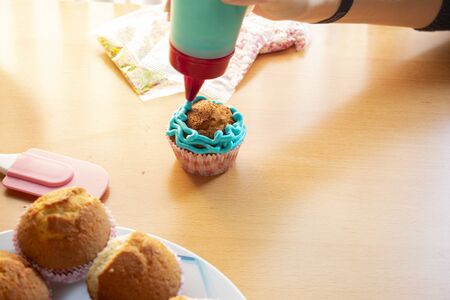 Apply blue cream to a homemade cupcakeの写真素材