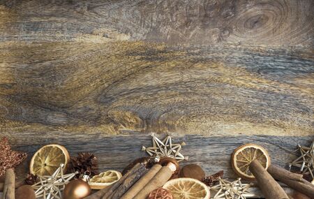 Christmas wood background with decorations of cinnamon sticks, dried orange slices and straw starsの写真素材