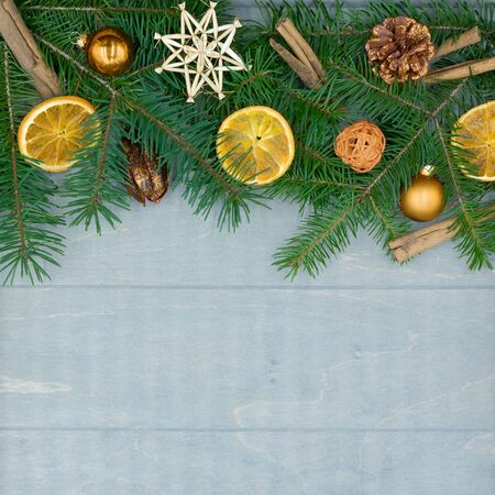 Christmas decorations of fir branches, dried oranges and cinnamon sticks on wood with copy spaceの写真素材
