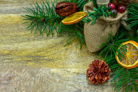 Wooden board with fir branches, dried oranges, cinnamon sticks and copy space in closeupの写真素材