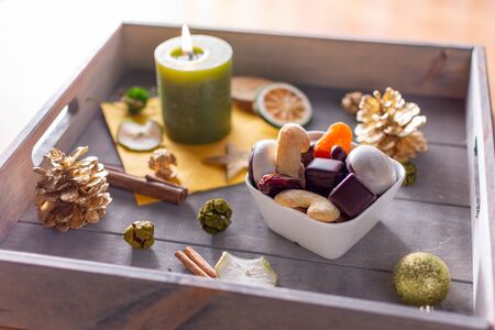 Small bowl of Christmas cookies on a wooden tray with burning candle and Christmas decorationsの写真素材