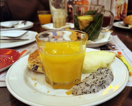 Breakfast table in the cafÃ© with fresh orange juice, fruit, chocolate rolls and teaの写真素材