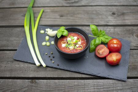Mediterranean tomato soup in a small bowl, decorated with garlic, spring onions and basil.の写真素材