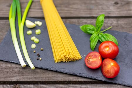 raw spaghetti decorated with spring onions, basil, tomatoes and garlic. Mediterranean foodの写真素材