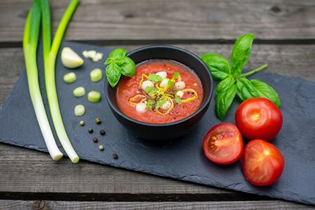 Mediterranean tomato soup with garlic, spring onions and basil served on a slate platterの写真素材