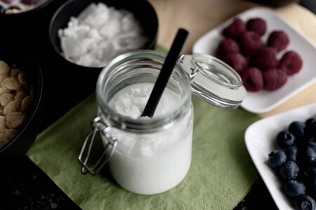 healthy coconut rice drink with coconut flakes in preserving jar with straw in desaturated coloursの写真素材