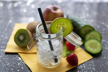 Preserving jar in close-up with crushred ice and kiwi disc. In the blurred background you can see fresh fruit and vegetables.の写真素材