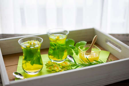 two freshly brewed teas of lemon balm and linseed in Turkish tea glasses on a trayの写真素材