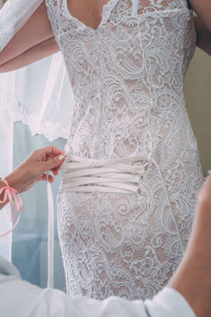 Bride putting on her white wedding dress.の写真素材