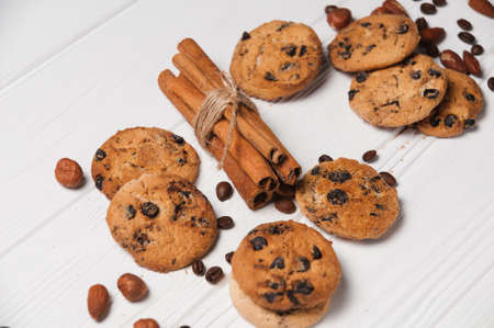 Homemade dessert biscuits on a white wooden background with cinnamon and nuts. Chocolate chip, oatmeal raisin, dough and nuts. Copy text menu food background.の写真素材
