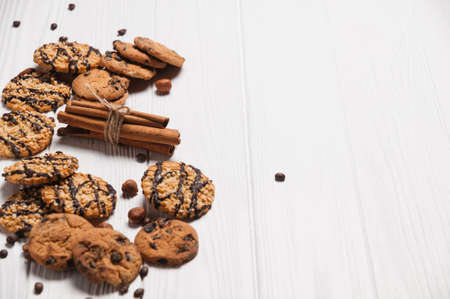 Homemade dessert biscuits on a white wooden background with cinnamon and nuts. Chocolate chip,...