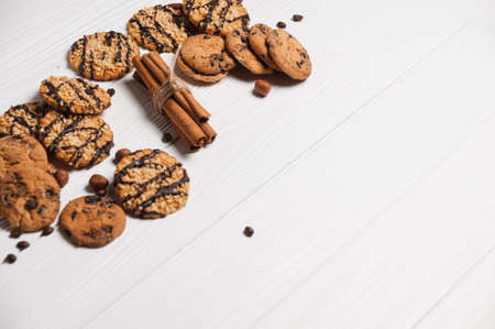 Homemade dessert biscuits on a white wooden background with cinnamon and nuts. Chocolate chip, oatmeal raisin, dough and nuts. Copy text menu food background.の写真素材