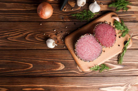 Smoked salami on an old wooden table. Sausages with rosemary, garlic and pepper and onions.の写真素材