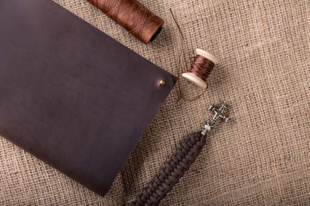 leather dark brown purse on a dark wooden background, with a thread and a needle