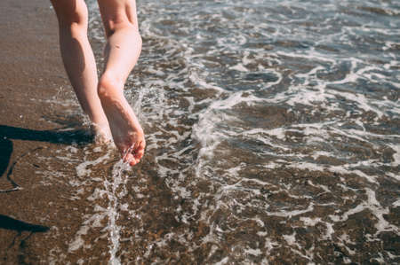 Young girl runs along the sea sandy beach barefoot, concept, legsの写真素材