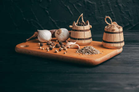 Spices: chili, black pepper, garlic, cumin, coriander, sweet pepper lie on a brown wooden board on a black table. Place under the textの写真素材