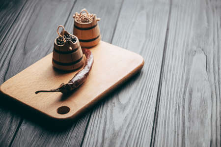 Spices: black pepper, red pepper, chili lie on a brown wooden board on a black table. Place under...