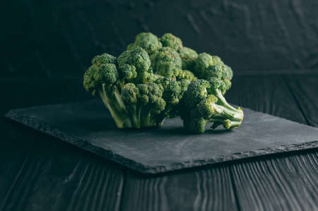 Fresh broccoli on a blackboard against a dark wood background. side view. place under the text. toningの写真素材