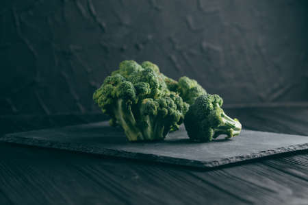 Fresh broccoli on a blackboard against a dark wood background. side view. place under the text. toningの写真素材