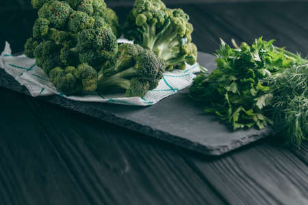 On a dark wooden table, fresh green broccoli, parsley, dill for your health. Flatlay. Recipe....