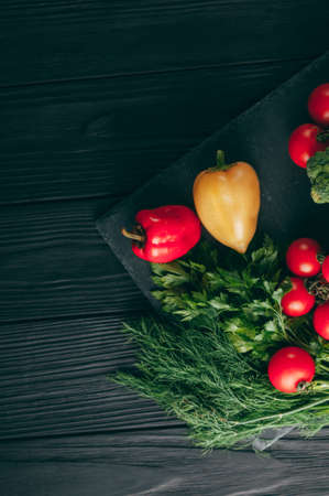Fresh vegetables: cherry tomatoes, broccoli, pepper, dill, parsley on a dark wooden table. Recipe....