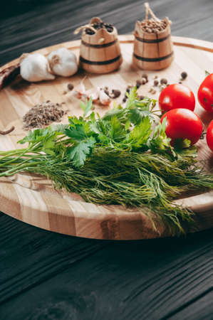 Spices: chili, black pepper, garlic, cumin, coriander, sweet pepper lie on a brown round wooden board on a black table. Place under the textの写真素材