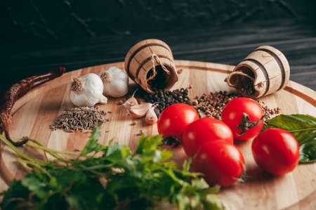 Spices: chili, black pepper, garlic, cumin, coriander, sweet pepper lie on a brown round wooden board on a black table. Place under the textの写真素材