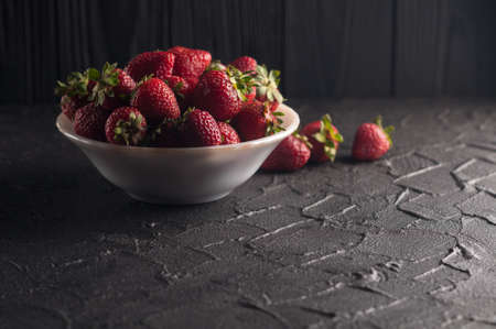 Fresh strawberries in a plate on a black backgroundの写真素材