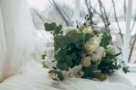 Beautiful wedding bouquet of white roses and orchids on an old classic white sofaの写真素材
