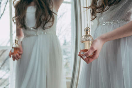 A girl in a white dress holds a bottle with perfumeの写真素材