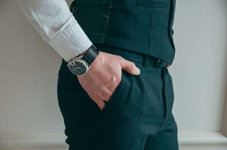The cut-off view of the boss, holding a jacket in his hands thrown over his shoulder, on his hand -...