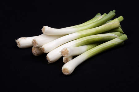 Fresh baby  leek  isolated on a black backgroundの写真素材