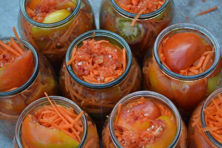 Natural products from the garden. Homemade food. Blanks for the winter. Marinated tomatoes. Grated carrot, Red and yellow tomatoes in jarsの写真素材
