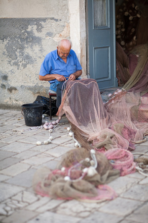old fisherman repairing fishing netのeditorial素材