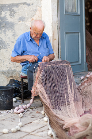Old fisherman repairing fishing netのeditorial素材