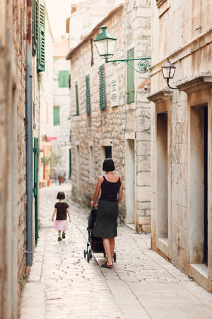 Mother and daughter walking the narrow streets of the old croatian town - view from the backsideの写真素材