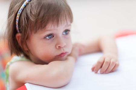 Cule little girl looking for someone or something at coffe table. Closeup portrait with shallow depth of fieldの写真素材
