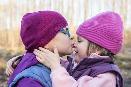 older sister lovingly kissing her younger sisterの写真素材