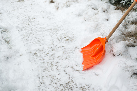 Snow removal. Orange Shovel in snow, ready for snow removal, outdoors.の写真素材