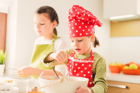 Two sisters preparing granola together. Happy siblings in the kitchen at home.の写真素材