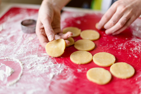cooking and home concept - close up of female hands making cookies from fresh dough at home - very...