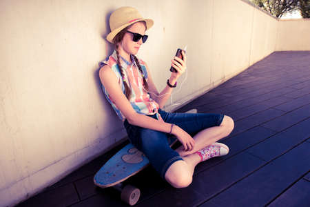 Hipster Girl Skateboarder listening to the music - Relax Lifestyle Concept -  toned with a retro vintage filterの写真素材