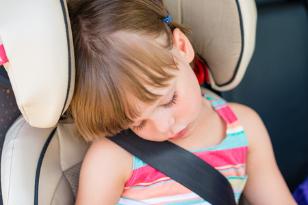Toddler girl asleep in a child safety seat in a carの写真素材