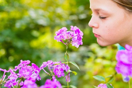 Young beautiful girl smells purple flowers in the garden - shallow depth of fieldの写真素材